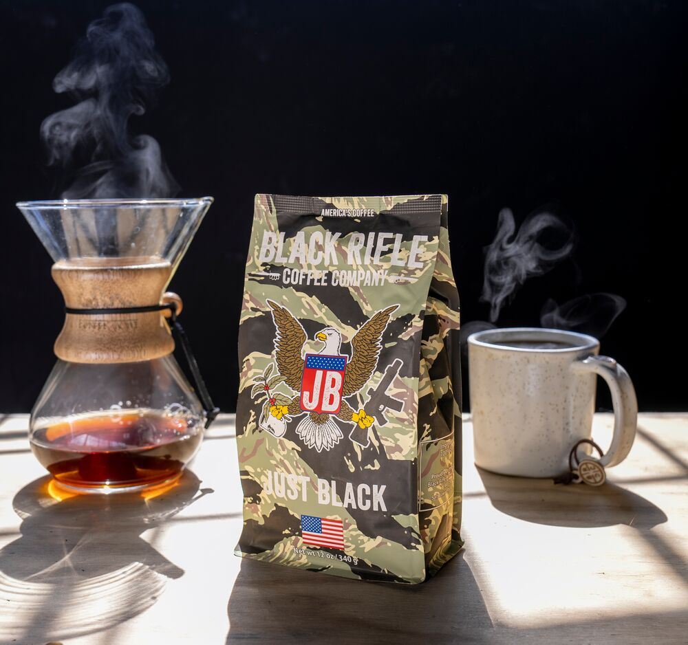 Black Rifle Coffee cup next to a French press in the outdoors